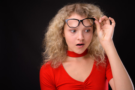 Young beautiful woman with blond curly hair against gray backgro