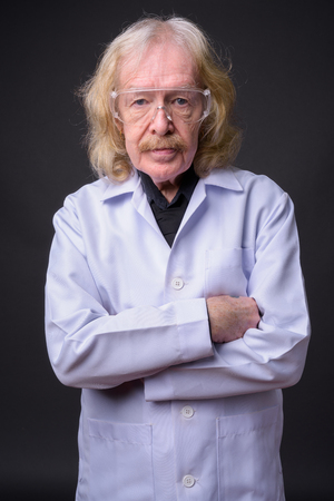 Senior man doctor with mustache wearing protective glasses againの写真素材