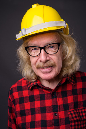 Senior man construction worker against gray backgroundの写真素材