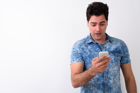 Young handsome Persian man using mobile phone against white backの写真素材