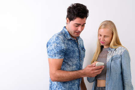 Young Persian man and beautiful blond woman against white backgr