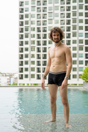Handsome bearded man shirtless relaxing beside the swimming poolの写真素材