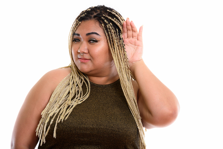 Studio shot of young fat Asian woman listeningの写真素材