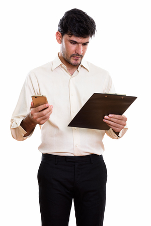 Studio shot of young Persian businessman reading on clipboard whの写真素材