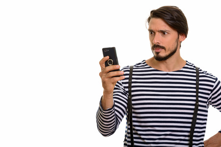 Studio shot of handsome man using mobile phone looking shockedの写真素材