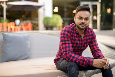 Young bearded Indian businessman relaxing at the mall in Bangkokの写真素材