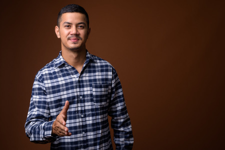 Young multi-ethnic Asian man against brown backgroundの写真素材