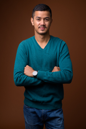 Young multi-ethnic Asian man against brown backgroundの写真素材