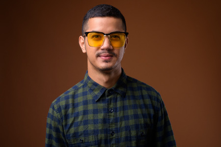 Young multi-ethnic Asian man against brown backgroundの写真素材