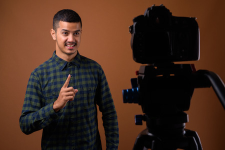 Young multi-ethnic Asian man against brown background