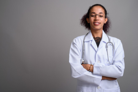 Young beautiful African woman doctor against gray backgroundの写真素材