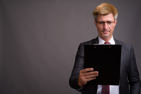 Businessman with blond hair against gray backgroundの写真素材