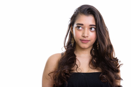Studio shot of young beautiful Indian woman thinking while lookiの写真素材