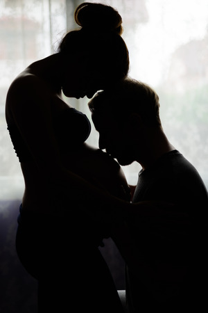 Multi-ethnic couple married and in love in silhouette by the winの写真素材