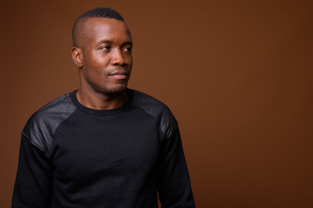 Studio shot of young African man against brown backgroundの写真素材