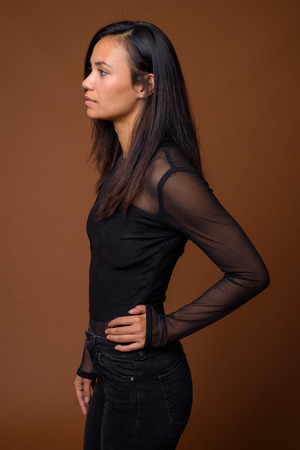 Studio shot of young Asian woman against brown backgroundの写真素材
