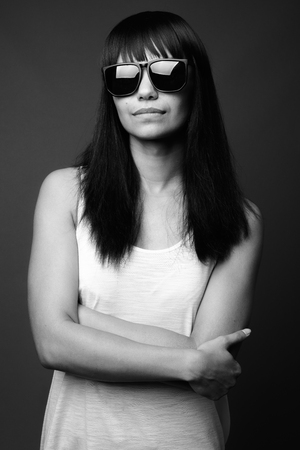 Young Asian woman against gray background in black and whiteの写真素材
