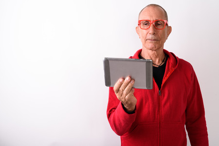 Studio shot of bald senior man using digital tablet while wearinの写真素材