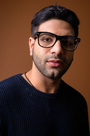 Young handsome Indian man against brown backgroundの写真素材