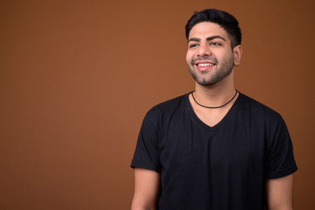 Young handsome Indian man against brown backgroundの写真素材