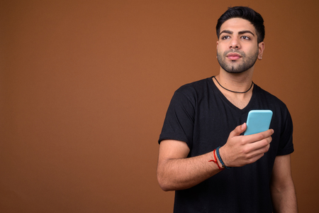 Young handsome Indian man against brown backgroundの写真素材