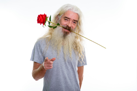 Studio shot of happy senior bearded man smiling while biting redの写真素材