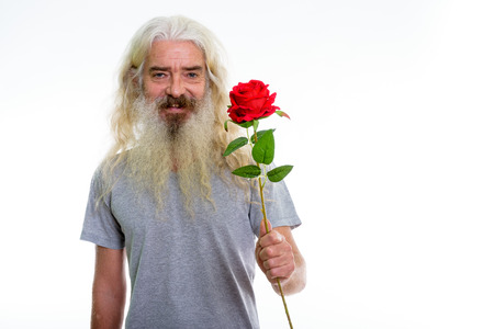Studio shot of happy senior bearded man smiling while giving red