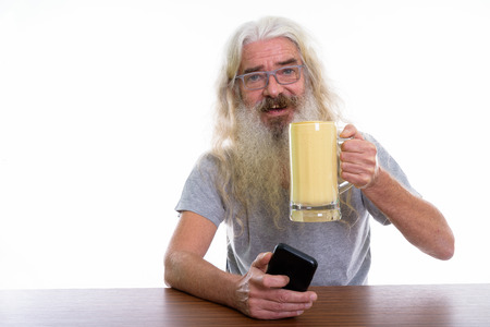 Studio shot of happy senior bearded man smiling while holding mo