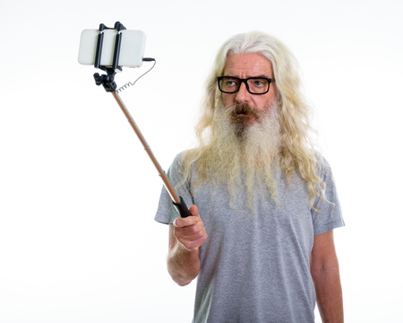 Studio shot of senior bearded man wearing eyeglasses and takingの写真素材