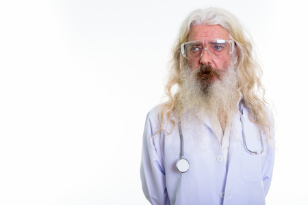 Studio shot of senior bearded man doctor thinking while wearingの写真素材