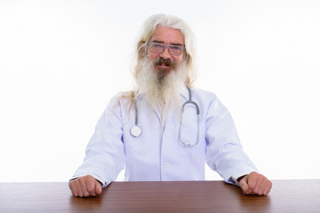 Studio shot of happy senior bearded man doctor smiling while  weの写真素材