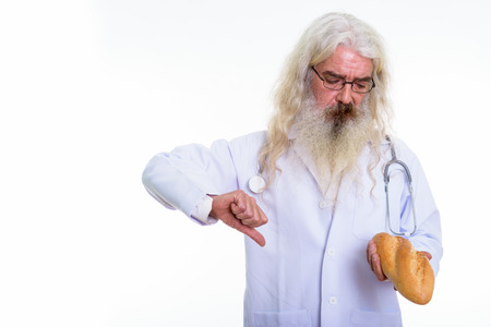 Studio shot of senior bearded man doctor wearing eyeglasses whilの写真素材