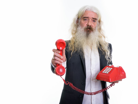 Studio shot of senior bearded businessman giving old telephone