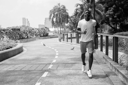 Black and white image of young African man running outdoors in parkの写真素材