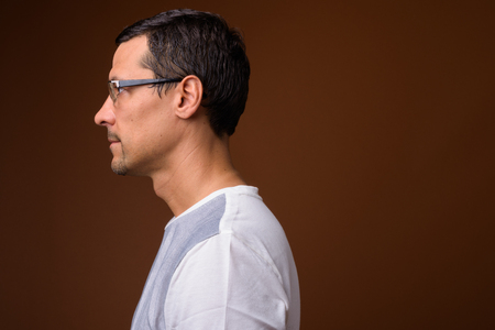 Profile view portrait of handsome man against brown backgroundの写真素材