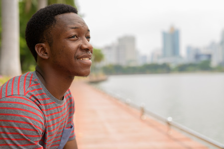 Young handsome African man relaxing and thinking at the parkの写真素材