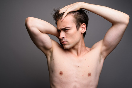Young handsome man shirtless against gray backgroundの写真素材