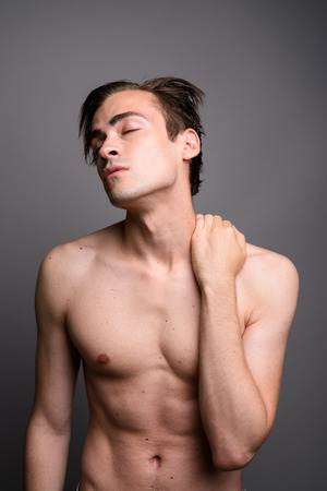 Young handsome man shirtless against gray backgroundの写真素材