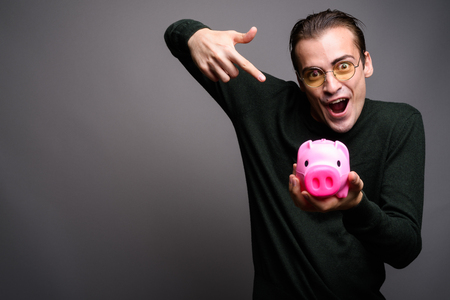 Portrait of young excited man holding piggy bankの写真素材