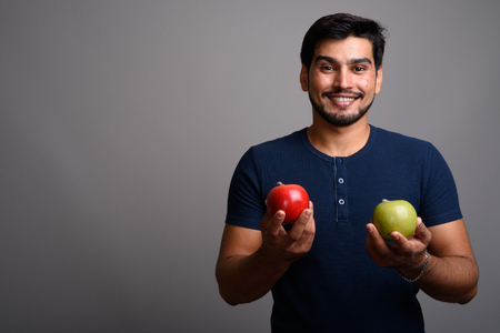 Young handsome bearded Persian man against gray backgroundの写真素材