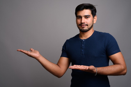 Young handsome bearded Persian man against gray backgroundの写真素材
