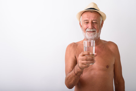 Shirtless senior man holding glass of waterの写真素材
