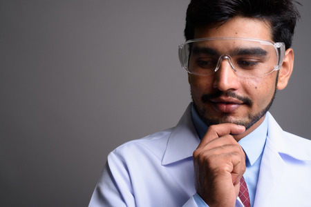 Young handsome bearded Persian man doctor wearing protective gla