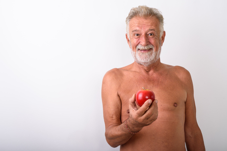 Happy senior bearded man smiling while holding red appleの写真素材
