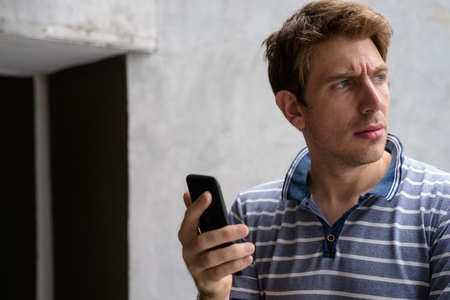Portrait of handsome man with blond hair against concrete wall outdoorsの写真素材