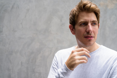 Portrait of handsome man with blond hair against concrete wall outdoorsの写真素材