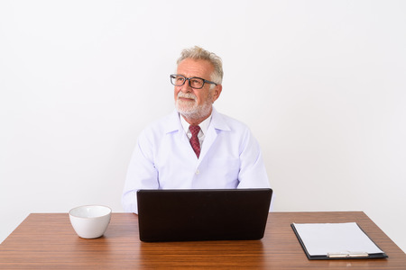 Studio shot of handsome senior bearded man doctor thinking while