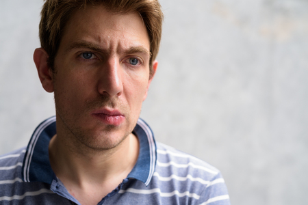 Portrait of handsome man with blond hair against concrete wall outdoorsの写真素材