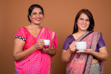 Two mature Indian women holding coffee or tea cupの写真素材