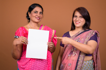 Two Indian woman holding empty white paper with copy spaceの写真素材